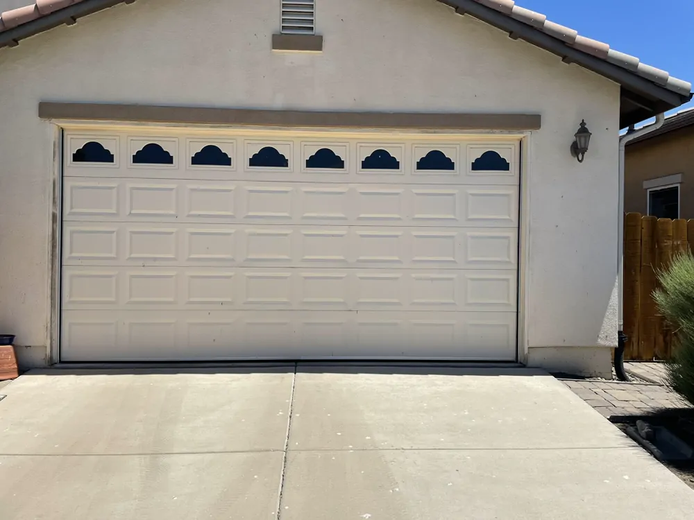 A double garage door on a stucco house, with the driveway in front.