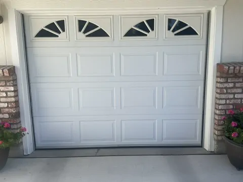 A single white garage door with arched windows, closed to the floor.